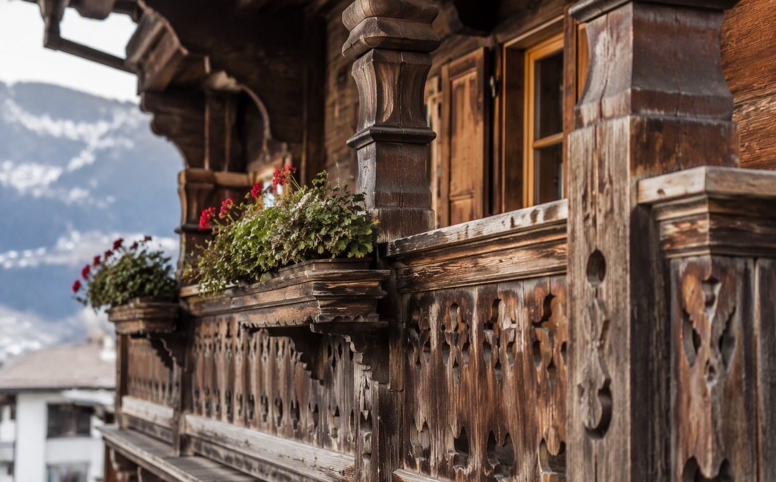 Hand-carved Tyrolean wooden balcony with geranium boxes on an Innsbruck apartment building